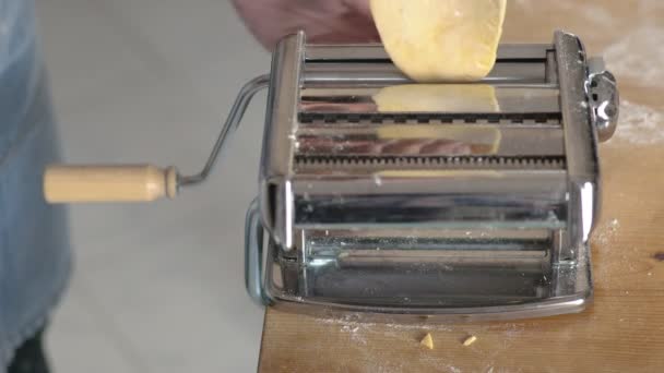 Homemade hands pass the dough into the machine to flatten it — Stock Video