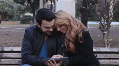 Genç çift tablet vasıl belgili tanımlık park fotoğraflarına bakmaktan gülüyor