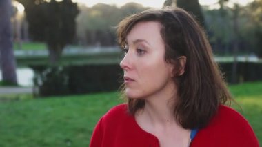 Kadın parkta biri için gözlerini ve ardından kamera gülümsüyor ile görünüyor