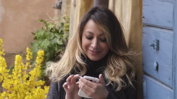 Ung blond kvinna ler medan du chattar med smartphone — Stockvideo