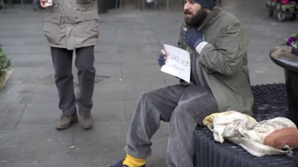 Mendigo sentado en la calle, el hombre le ayuda con la comida y el café — Vídeos de Stock