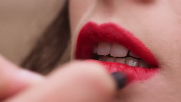 Одягаючи червону помаду на губи жінки, візажист працює — стокове відео