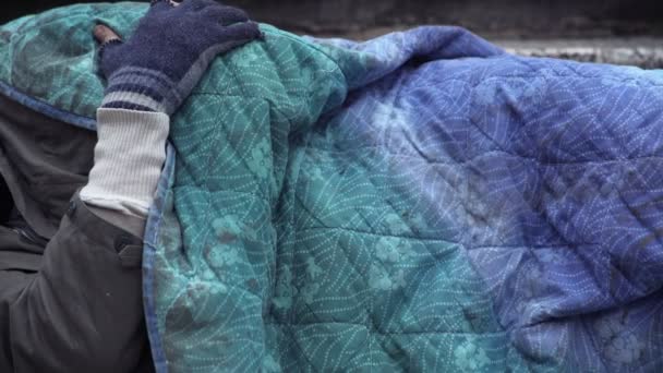 Obdachloser schläft, während unbekannte Hand ihn weckt und Almosen hinterlässt
