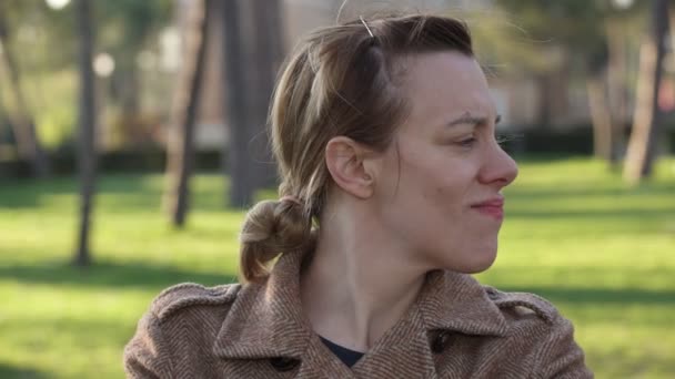 Vrouw in het park te wachten tot iemand, kijkt naar de camera en begint lachen — Stockvideo