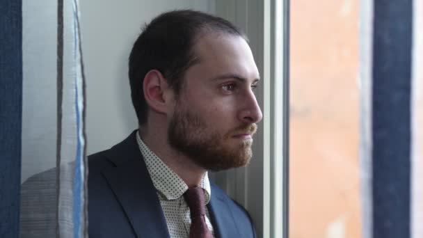 Задумчивый и серьезный бизнесмен смотрит в окно — стоковое видео