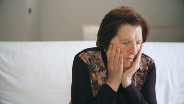 Ledsen och orolig gammal kvinna sitter i soffan — Stockvideo