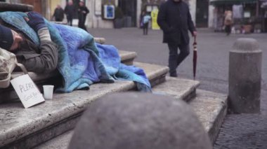 portrait of homeless man sleeps on the stairs of a fountain, while a pedestrian 