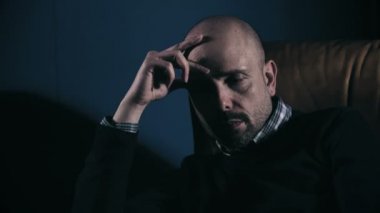 Kaygılı ve karanlık koltukta oturan düşünceli adam portresi