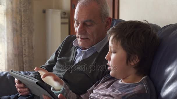 Grandchild with grandpa on the couch use the tablet — Stock Video