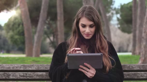 Красивая женщина сидит скамейка с помощью планшета — стоковое видео