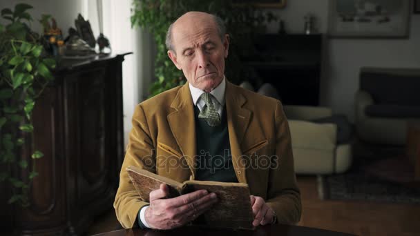 Портрет элегантного пожилого человека читает книгу, в помещении — стоковое видео