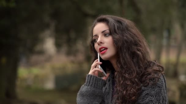 Piękna kobieta, nerwowo rozmawia przez telefon, w parku — Wideo stockowe