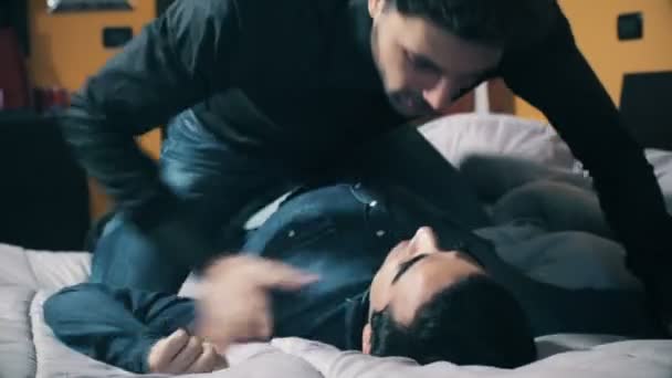 Борьба между мужчинами на кровати, которая заканчивается поцелуем — стоковое видео
