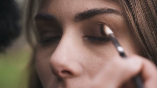 Artista de maquillaje aplicando con sombra de ojos de cepillo en mujer joven — Vídeos de Stock