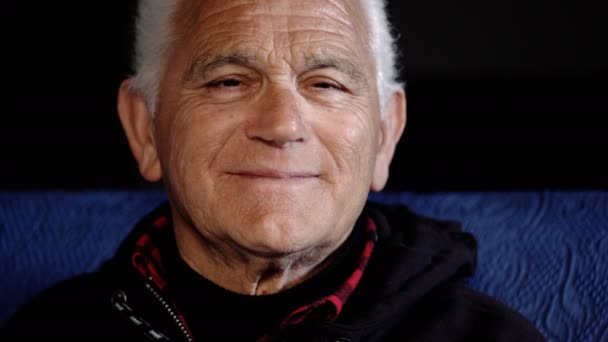 Портрет улыбающегося старика, смотрящего в камеру, в помещении — стоковое видео