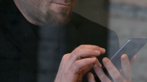 ビジネスマンのガラスの後ろに、スマート フォンでメッセージを送信するのにクローズ アップ — ストック動画