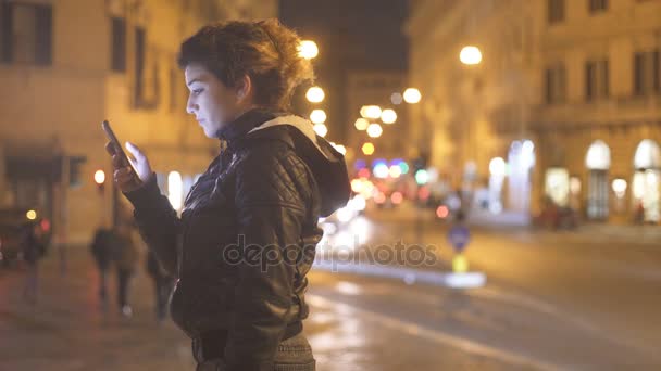 Мила жінка в профілі написання повідомлення на смартфоні, що стоїть в місті ближче — стокове відео