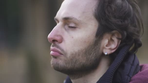 Close up on sad and thoughtful man looks at the camera, outdoor — Stock Video