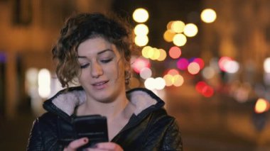 Güzel kız bir mesaj ile smartphone, gece şehri içinde adam yazar