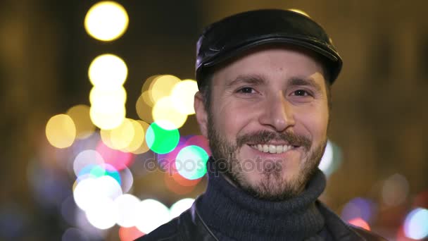 Lächelnder und charmanter Mann blickt in die Kamera, Stadt bei Nacht — Stockvideo