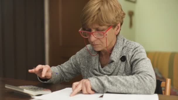 Femme blonde avec des lunettes concentrées sur le calcul des factures — Video