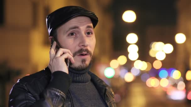 Homem sorridente falando ao telefone na cidade à noite — Vídeo de Stock