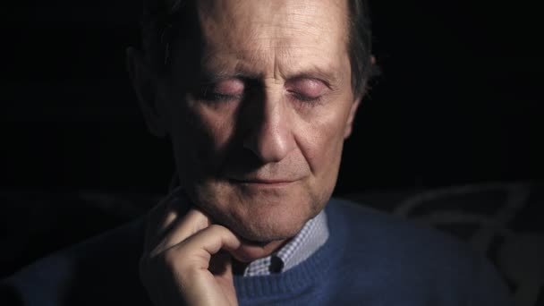 Портрет пожилого человека, переживающего и грустного в темноте, закрывающего глаза — стоковое видео