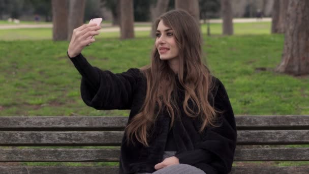 Joven hermosa mujer Fotografías con Smartphone (Selfie) en el parque — Vídeos de Stock