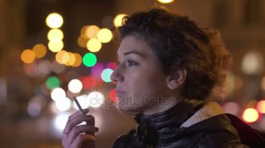 Üzgün ve düşünceli yalnız kadın gece şehirde bir sigara içiyor