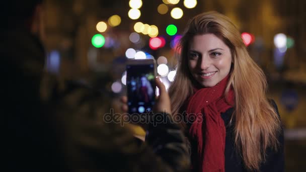 S úsměvem mladá žena, zatímco její přítel ji fotografie s chytrým telefonem — Stock video