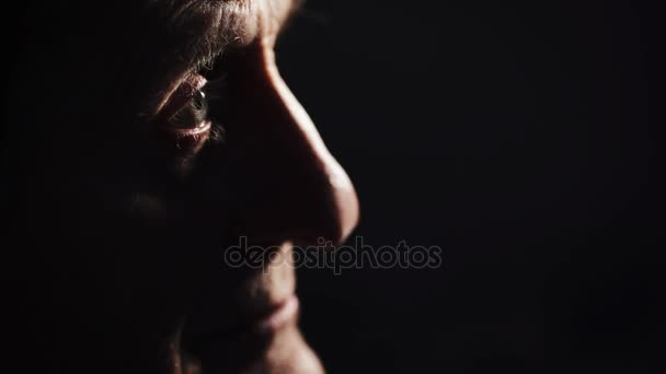 Szomorú és átgondolt öreg a sötétben, profil közelről — Stock videók