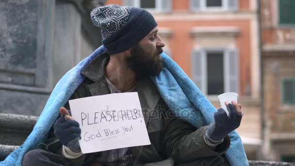 Portrait of homeless sitting in the street receives a coin from a person — Stock Video