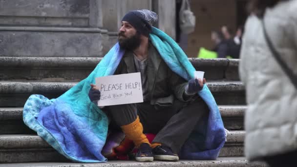 Sad and desperate beggar sitting on the steps begging alms — Stock Video