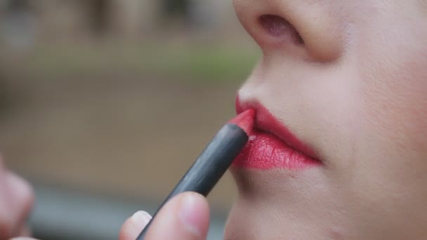 Make-up artiest rood potlood is van toepassing op de lippen van een model — Stockvideo