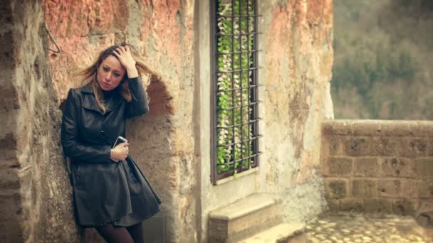 Депрессивная грустная женщина отдыхает на стене в ветреный день — стоковое видео