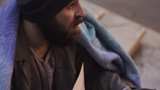 Жебрак, сидячи на вулиці отримує монету з людини — стокове відео