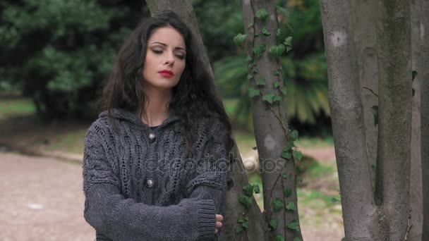 Traurige und melancholische Brünette im Park. Porträt einer depressiven jungen Frau — Stockvideo