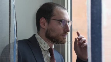 Düşünceli ve ciddi bir işadamı pencereden görünüyor