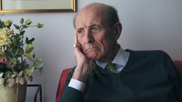 Печальный и обеспокоенный портрет старика: грустный старик сидит на диване — стоковое видео