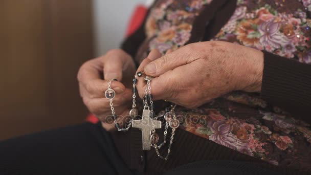 Nahaufnahme einer alten Frau, die beim Gebet den Rosenkranz ergreift — Stockvideo