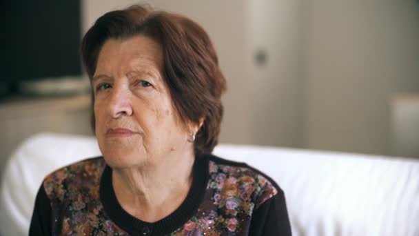 Tankeväckande gammal kvinna i hennes tankar som sitter i soffan, porträtt — Stockvideo
