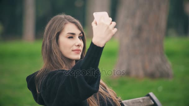 Glückliche schöne Frau, die auf der Bank sitzt, schießt lustige Selfies — Stockvideo