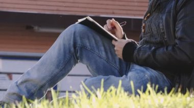 genç adamın elini bir ağacın altında oturup bir defter yazma