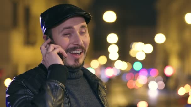Avslappnat leende ung man pratar i telefon i staden på natten — Stockvideo