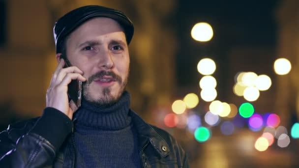 Lächelnder gutaussehender Mann, der in der Nacht in der Stadt telefoniert — Stockvideo
