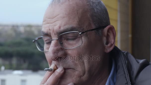 Θλιβερή στοχαστικό γέρος που καπνίζει ένα τσιγάρο σε μπαλκόνι-σταθερή κάμερα — Αρχείο Βίντεο