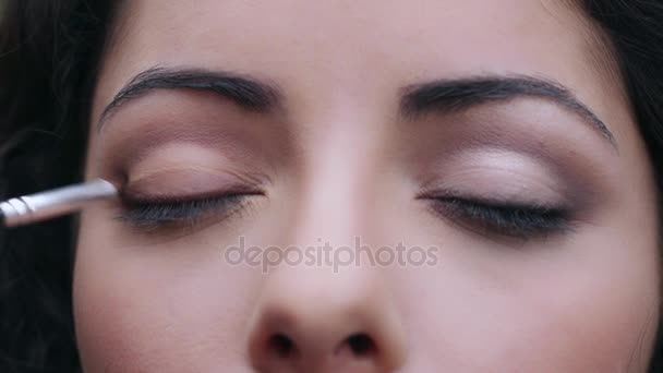 Make-up artiest toe te passen met borstel corrector op mooie vrouw gezicht, close-up — Stockvideo
