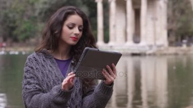 Düzülmüş gülümseyen esmer tablet vasıl belgili tanımlık park, lake arka planda kullanır
