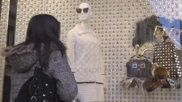 Young woman in front of a shop window of a clothes shop — Stock Video