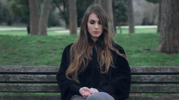 Traurig gelangweilte süße Frau allein auf einer Bank im Park — Stockvideo